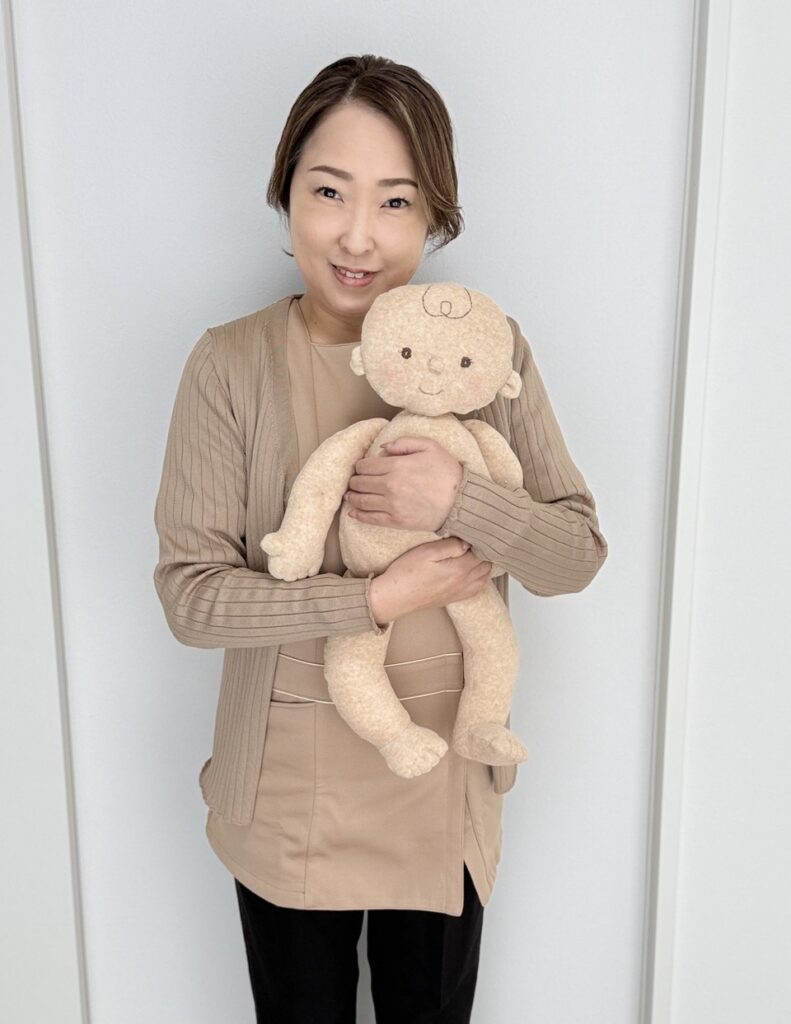 代表　赤ちゃん人形を持って講義完了のお知らせ